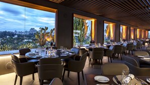 En moderne restaurant med et stort spiseområde, store vinduer og udsigt over byen.