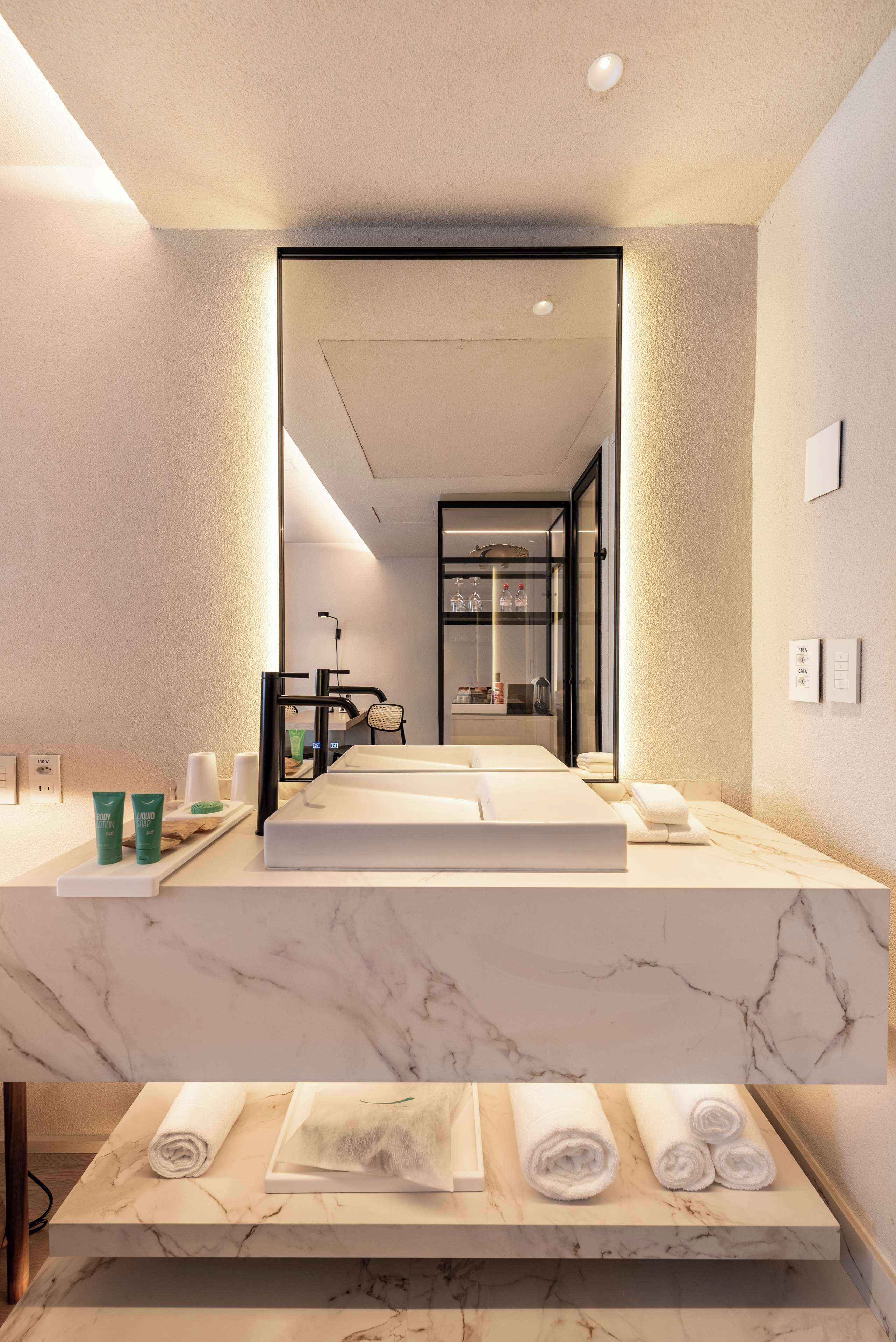 Un baño moderno con un espejo grande, encimera de mármol y toallas ordenadas.