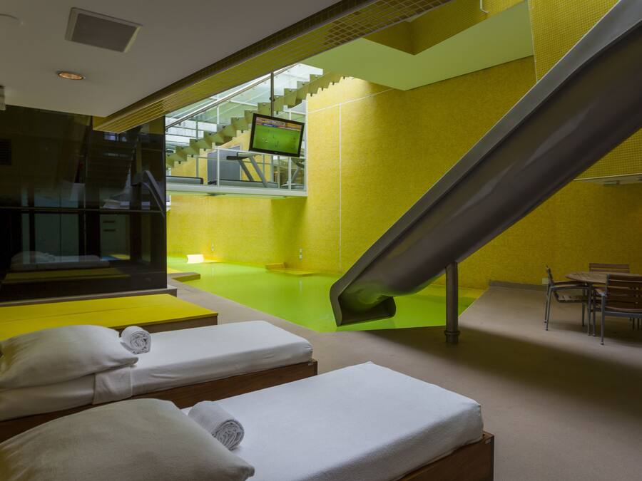 A hotel room with a large window, a bed, a chair, and a small table.