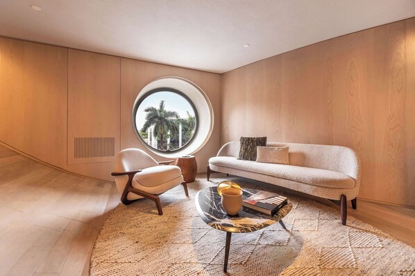A modern living room with a round window, a sofa, a chair, and a coffee table.