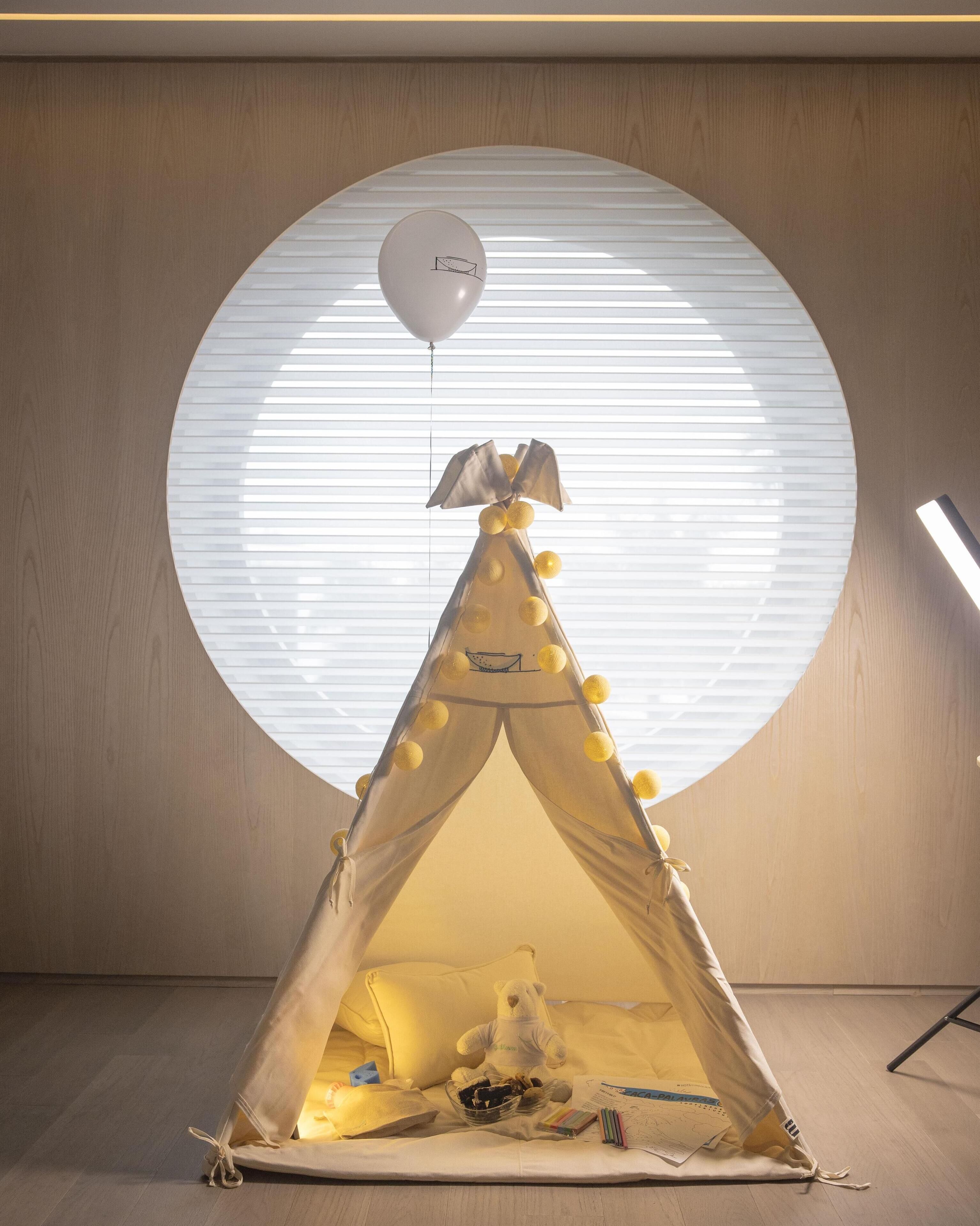A tent with a balloon, a teddy bear, and a map on the floor.