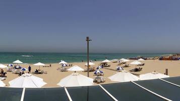 Pantai di sekitar, pasir putih, dan payung pantai