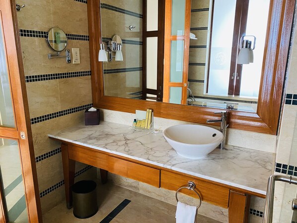 A bathroom with a marble sink, wooden vanity, and a large mirror.