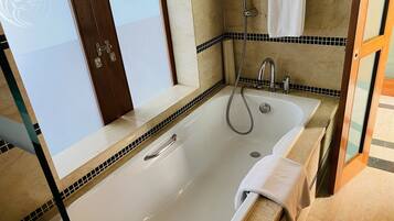 A bathroom with a large bathtub, a shower, and a sink.