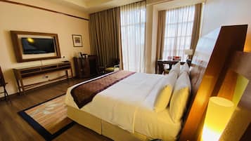 A hotel room with a large bed, a television, a desk, and a telephone.