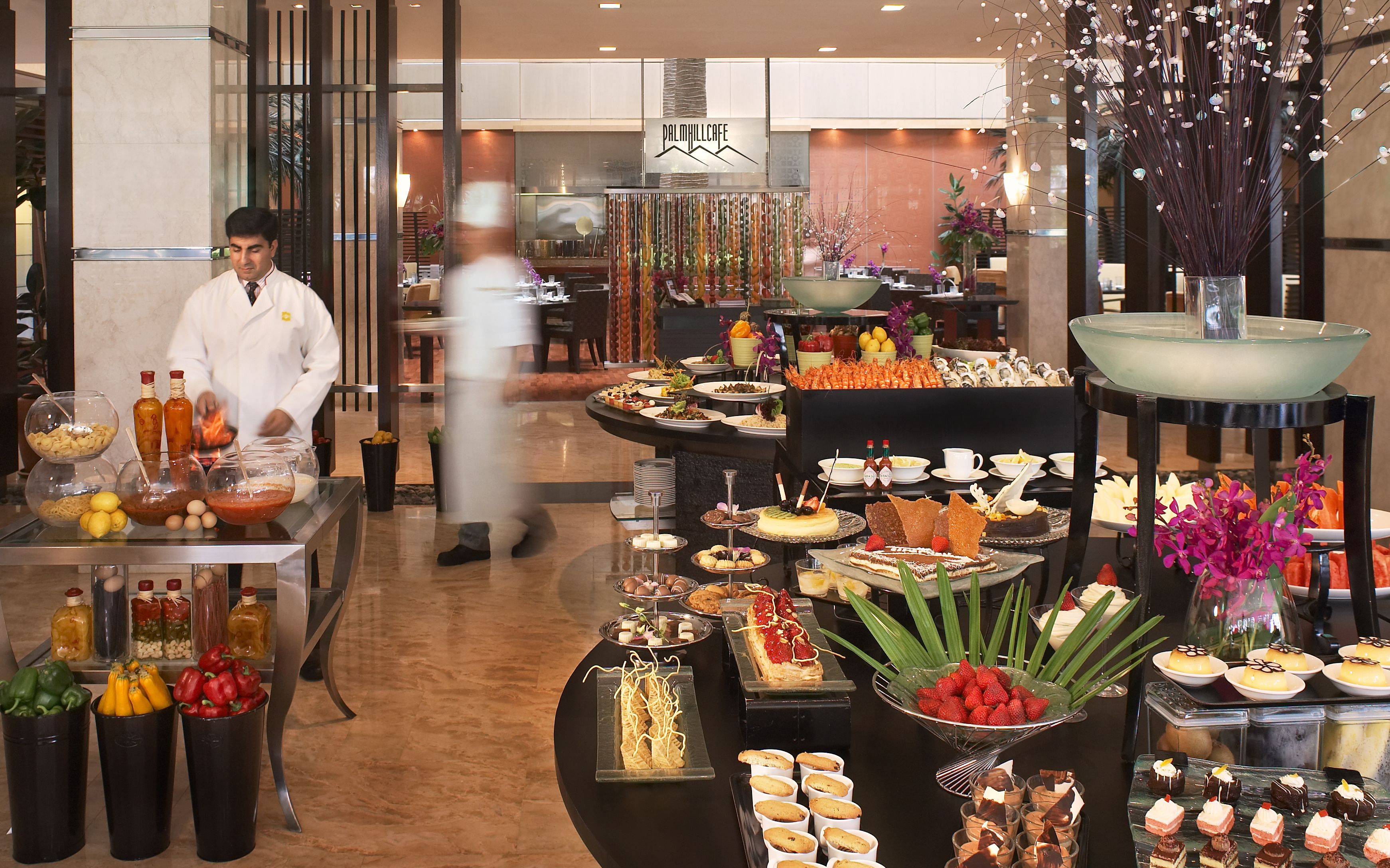 A buffet area with various food items and a chef preparing food.