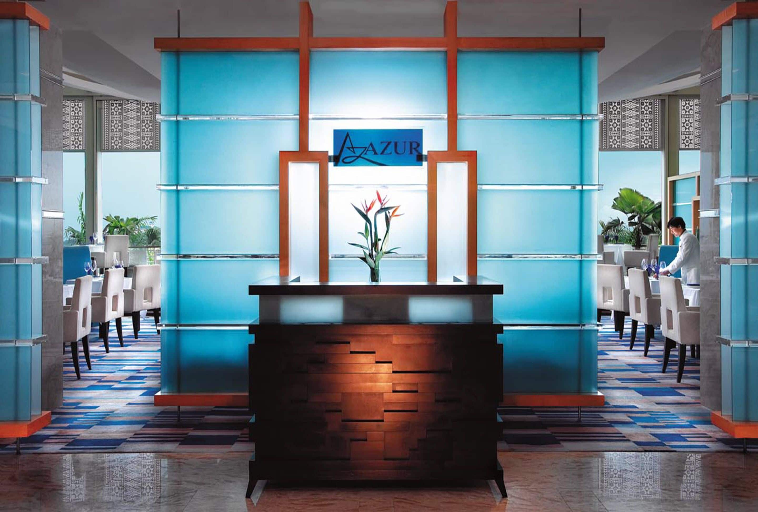 Un área de recepción con una decoración azul y blanca, un mostrador de madera y un letrero que dice "AZUR".