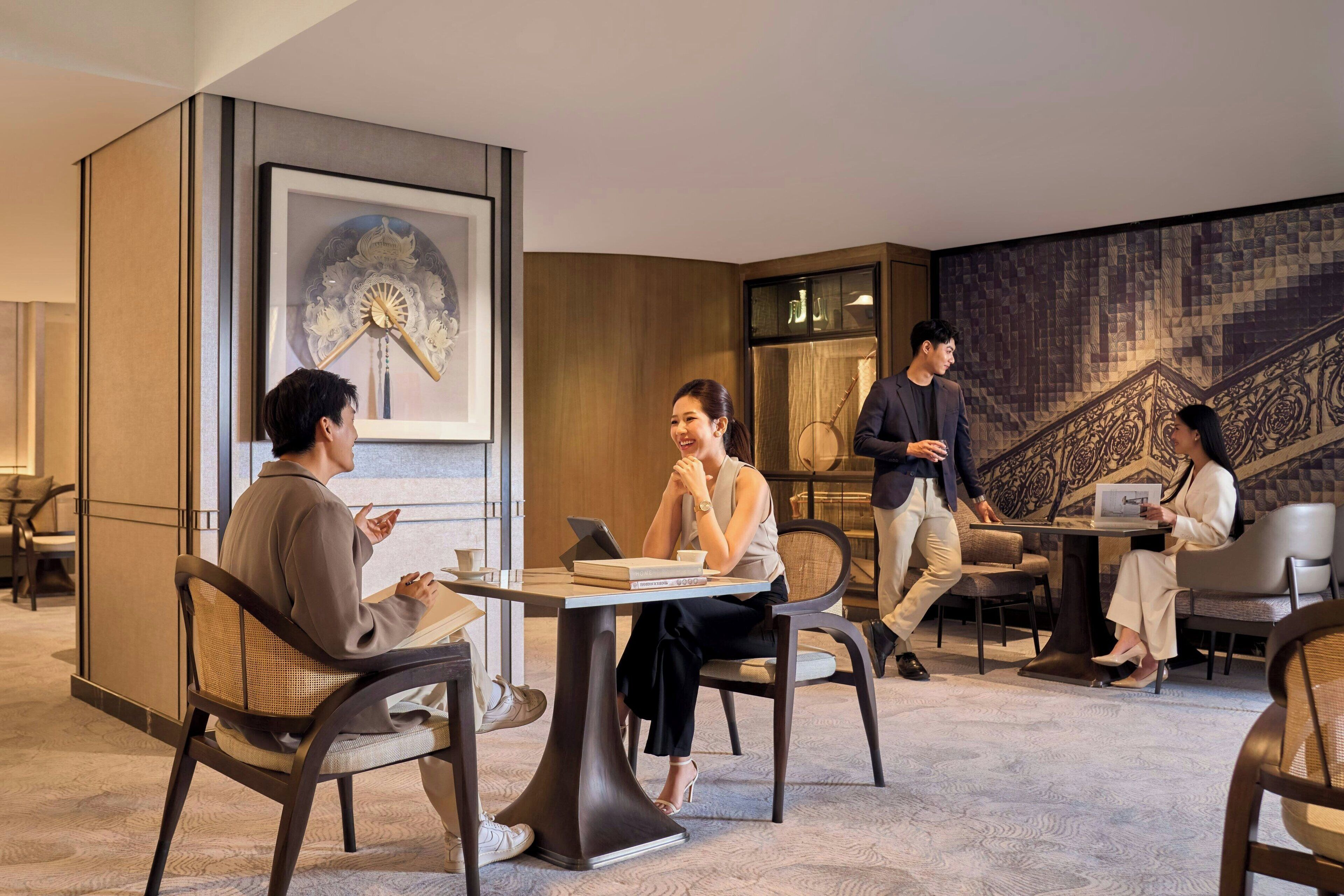 Un hall d’hôtel moderne, doté d’une grande horloge, de sièges confortables et d’une fresque murale décorative.