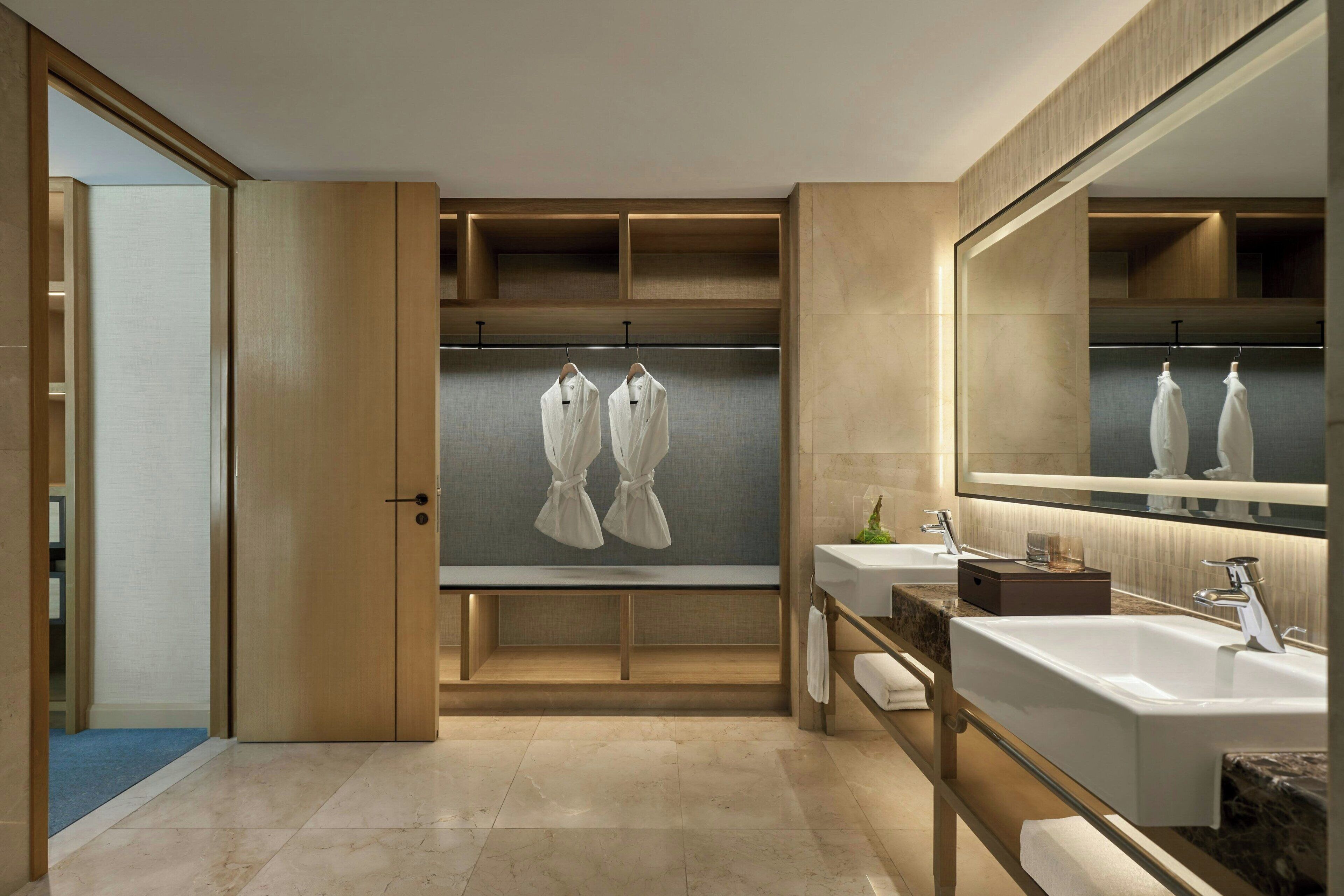 A modern bathroom with two sinks, a large mirror, and wooden cabinets.