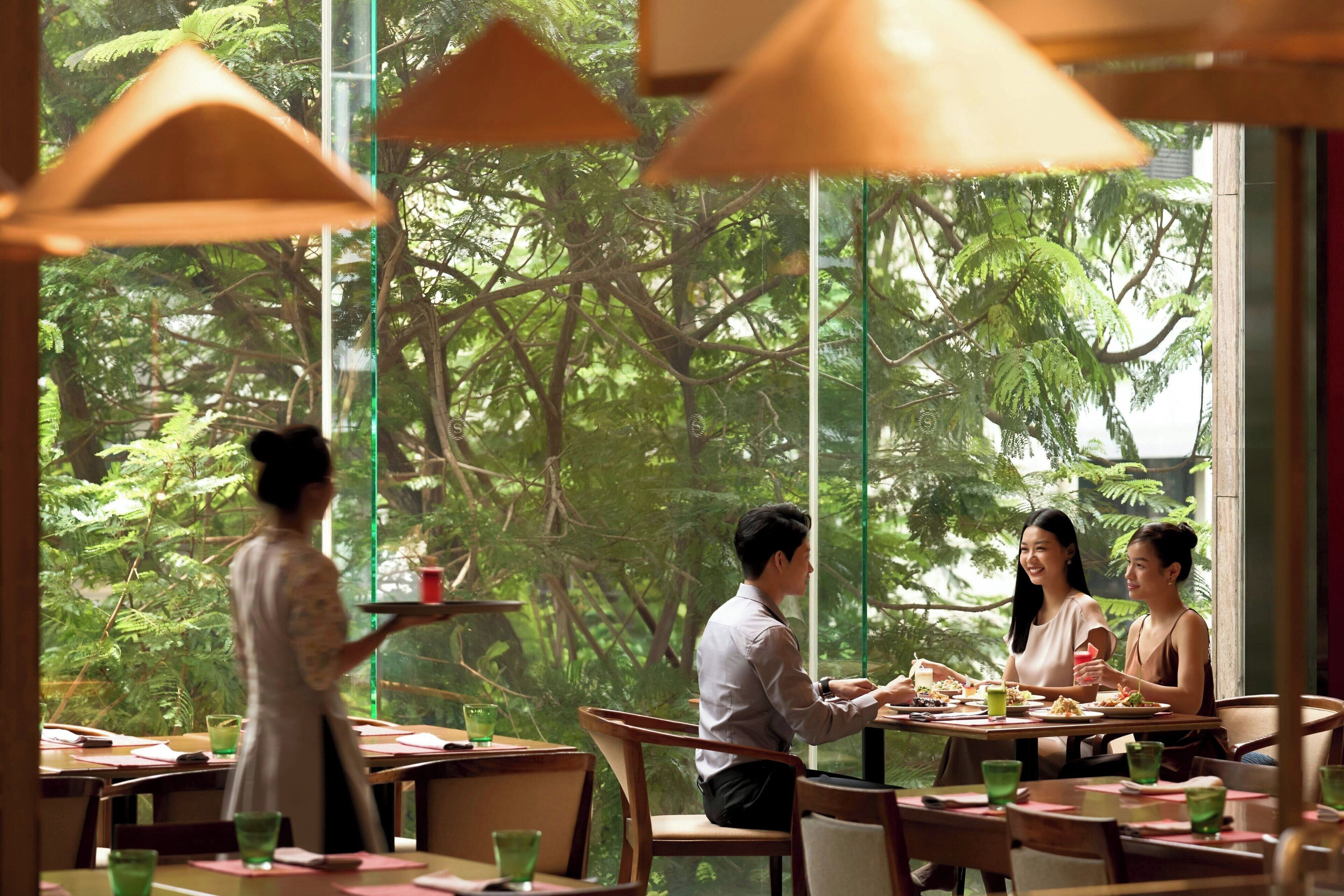 Ein Restaurant mit großen Fenstern, Holztischen und -stühlen.