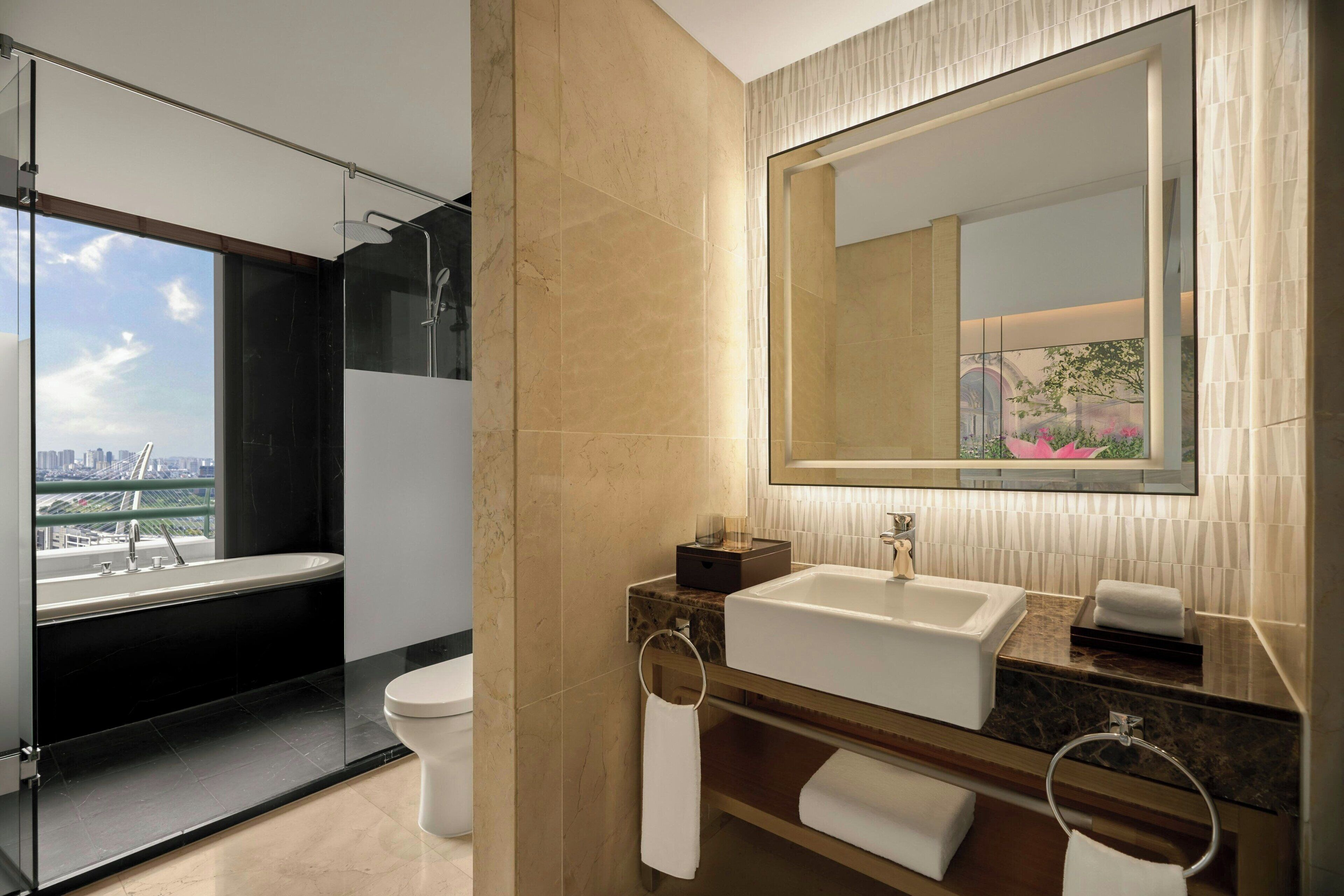 A modern bathroom with a large mirror, a bathtub, and a sink.
