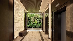 A modern hallway with a marble floor, a green wall with plants, and a wooden ceiling.