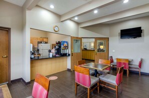 A restaurant with wooden furniture, a counter with a coffee machine, and a clock on the wall.