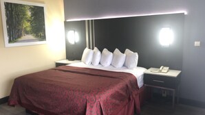Una habitación de hotel con una cama grande, una mesita de noche con teléfono y un cuadro en la pared.