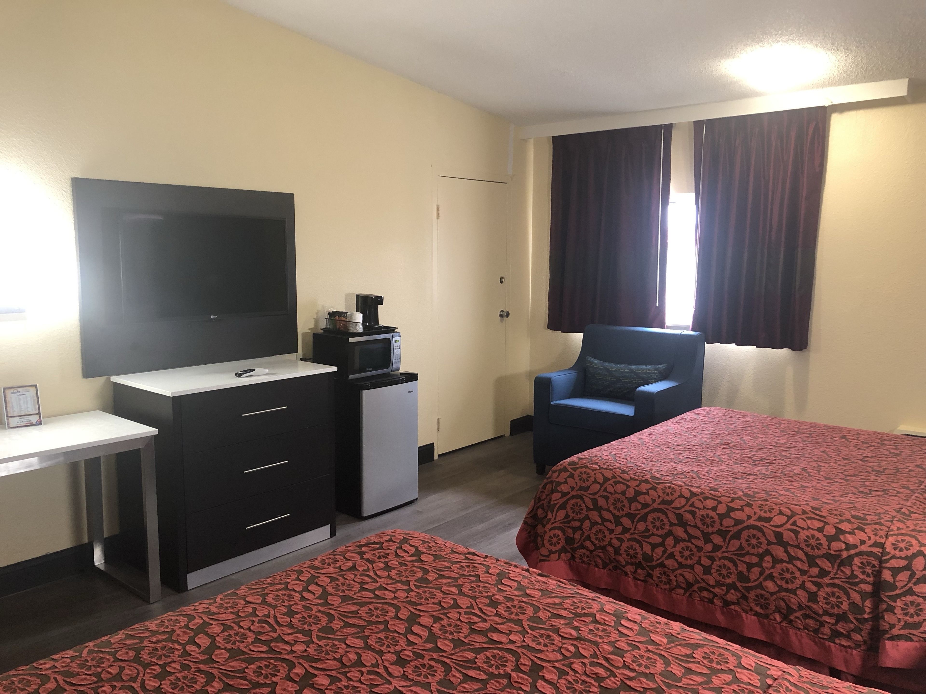 Habitación de hotel con dos camas, un escritorio, televisión, mini refrigerador y una silla.