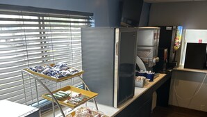 Zona de bufé con fuentes de comida, un refrigerador y un microondas.