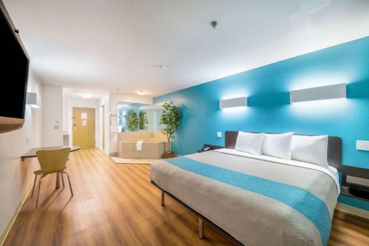 Una habitación de hotel con una cama, un escritorio, una silla y una televisión.
