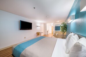 A hotel room with a large bed, a flat-screen TV mounted on the wall, a small table, and a chair. - Motel 6 Decatur, TX (Decatur)