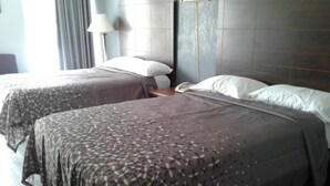 A hotel room with two beds, each with a patterned bedspread, a bedside table with a lamp, and a headboard with a telephone. - Budget Inn Express (Anderson)