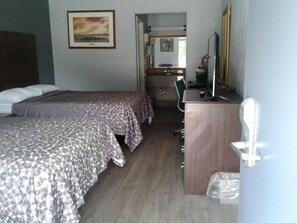 A hotel room with two beds, a desk, a chair, a mirror, and a television.