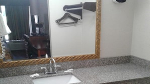 A bathroom with a granite countertop, a sink, a mirror with a gold frame, and a hairdryer mounted on the wall. - Budget Inn Express (Anderson)
