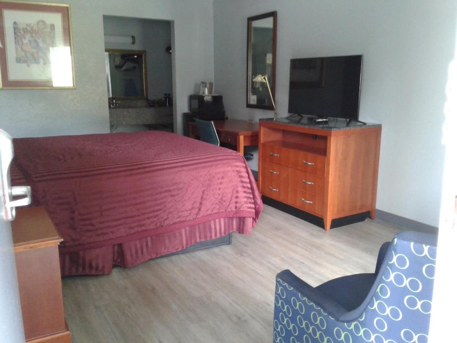 Una habitación de hotel con cama, escritorio, televisor y una silla.