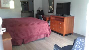 A hotel room with a bed, a desk, a television, and a chair.