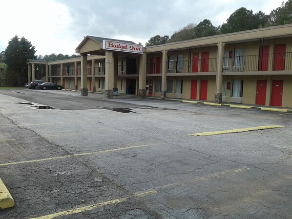 Un motel con un letrero que dice "Budget Inn" y varias habitaciones con puertas rojas.