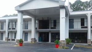 A multi-story motel with a central entrance, balconies, and potted plants. - Budget Inn Express (Anderson)