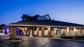 A hotel with a stone facade, a covered entrance, and a sign indicating a clearance height of 9 feet. - Best Western DeWitt (DeWitt)