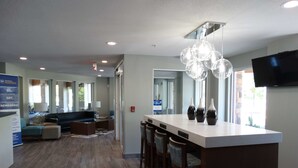 A modern kitchen with a central island, bar stools, and pendant lighting. - Best Western DeWitt (DeWitt)