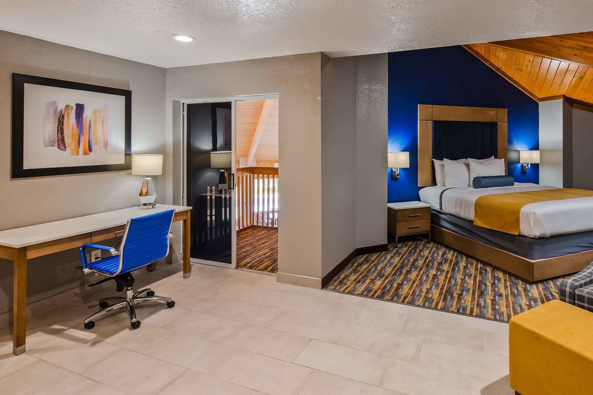 A hotel room with a desk, chair, bed, and a sofa.