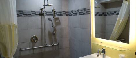 Un baño con ducha, lavamanos y espejo.