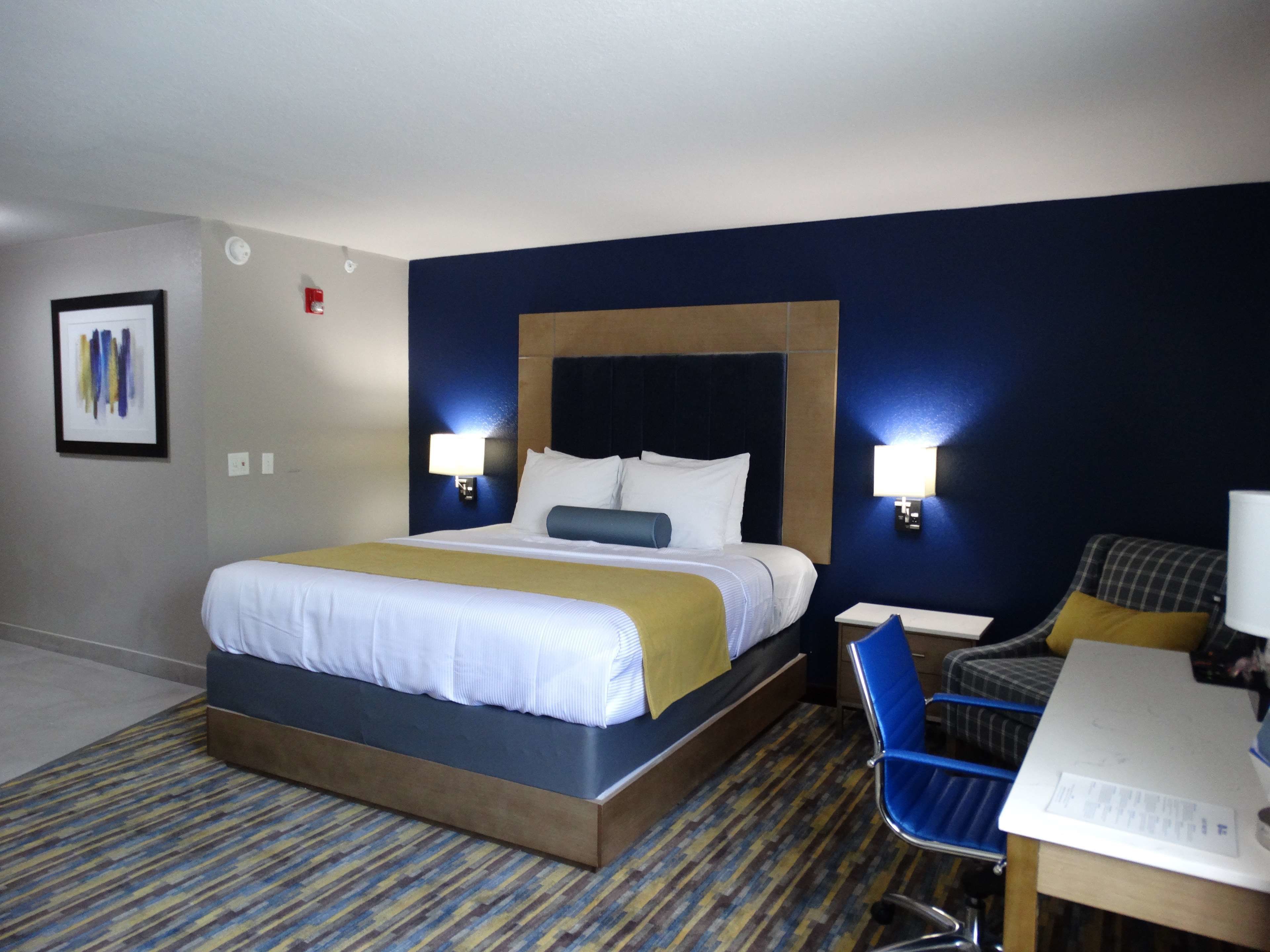 A hotel room with a large bed, two bedside tables, a desk, and a chair.
