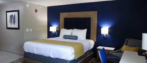 A hotel room with a large bed, two bedside tables, a desk, and a chair.