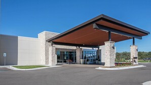 A modern building with a covered entrance, stone pillars, and a clear blue sky. - Holiday Inn Express & Suites Ludington by IHG (Ludington)
