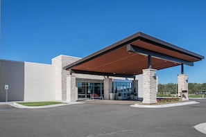 A modern building with a covered entrance, stone pillars, and a clear blue sky. - Holiday Inn Express & Suites Ludington by IHG (Ludington)