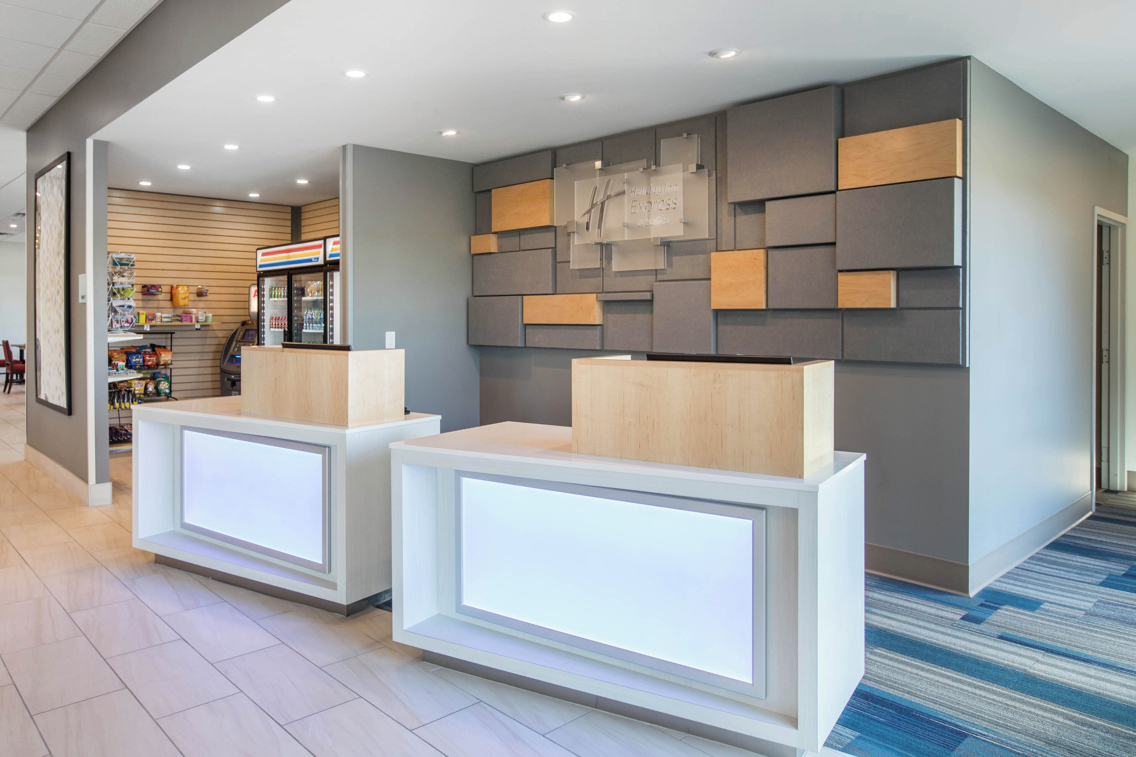 A reception area with two reception desks, a vending machine, and a wall with a geometric pattern.
