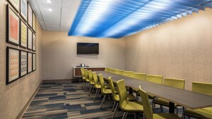 A conference room with a long table, yellow chairs, a flat-screen TV, and framed artwork on the wall. - Holiday Inn Express & Suites Ludington by IHG (Ludington)