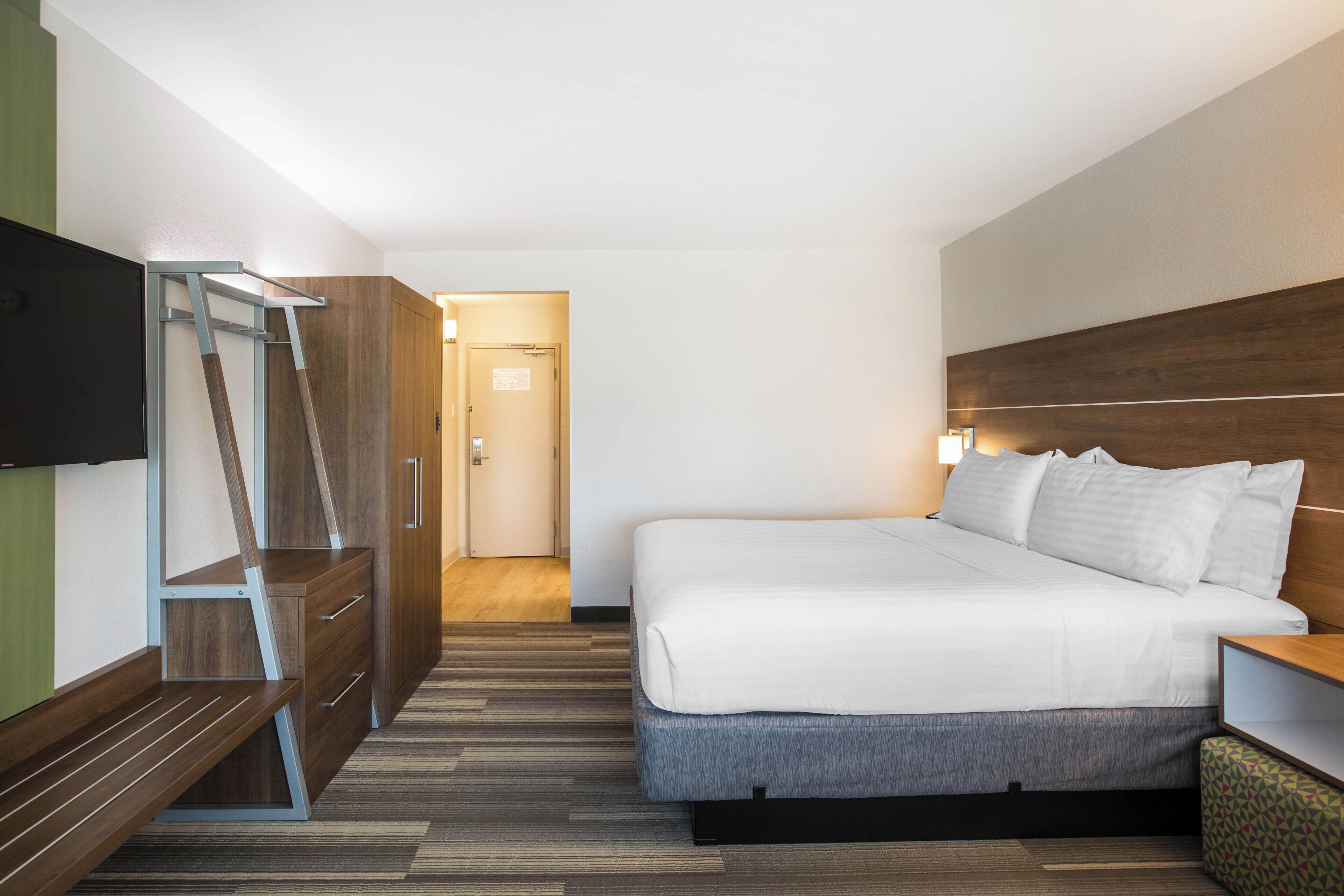 Una habitación de hotel con cama, televisión, escritorio y armario.