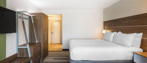 Una habitación de hotel con cama, televisión, escritorio y armario.