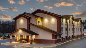 A multi-story hotel with a central staircase, outdoor seating area, and a covered entrance.
