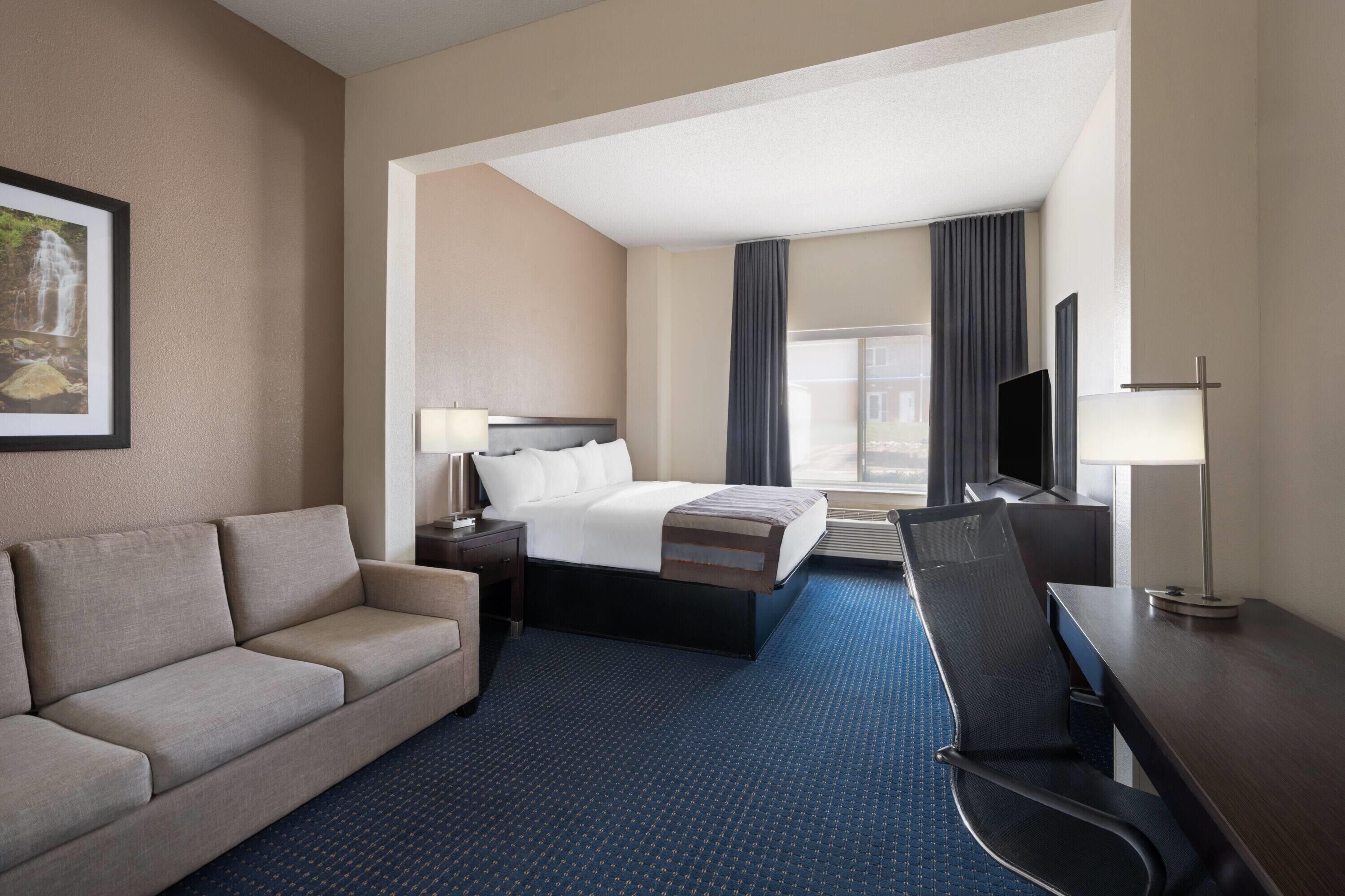 Een hotelkamer met een bed, een bureau, een stoel, een bank en een televisie.