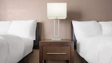 A hotel room with two beds, a nightstand with a lamp, and a small drawer.