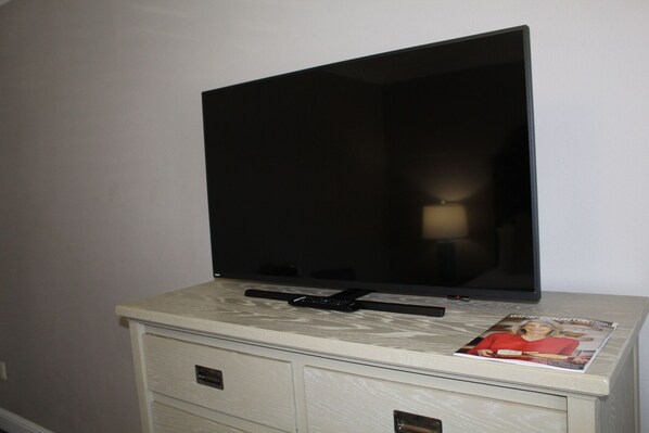 Un televisor de pantalla plana sobre un mueble con una revista encima.