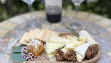 Une planche en bois garnie de fromage, de crackers, de miel en rayon, de fleurs et de noix, posée sur une table carrelée.