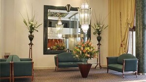 A lobby with a green sofa, a coffee table with flowers, a mirror, and two floor lamps. - Abasto Hotel (Buenos Aires)