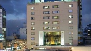 A multi-story hotel with a prominent rooftop sign, a ground-level entrance, and a visible interior space with seating. - Abasto Hotel (Buenos Aires)