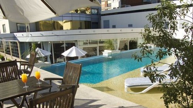 A pool area with lounge chairs, a table with drinks, and umbrellas. - Abasto Hotel (Buenos Aires)