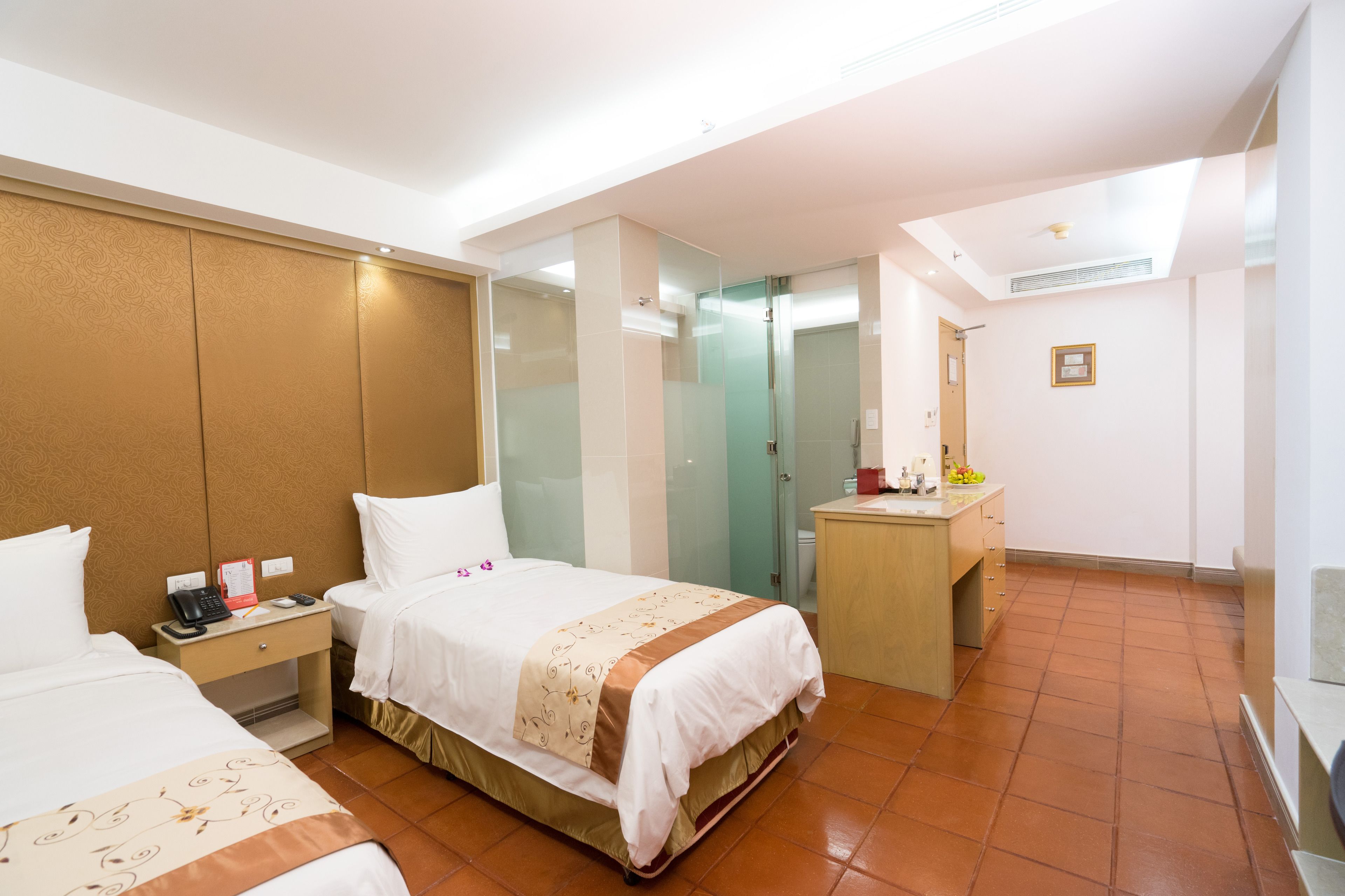 Habitación de hotel con dos camas, un escritorio, un espejo y un baño.